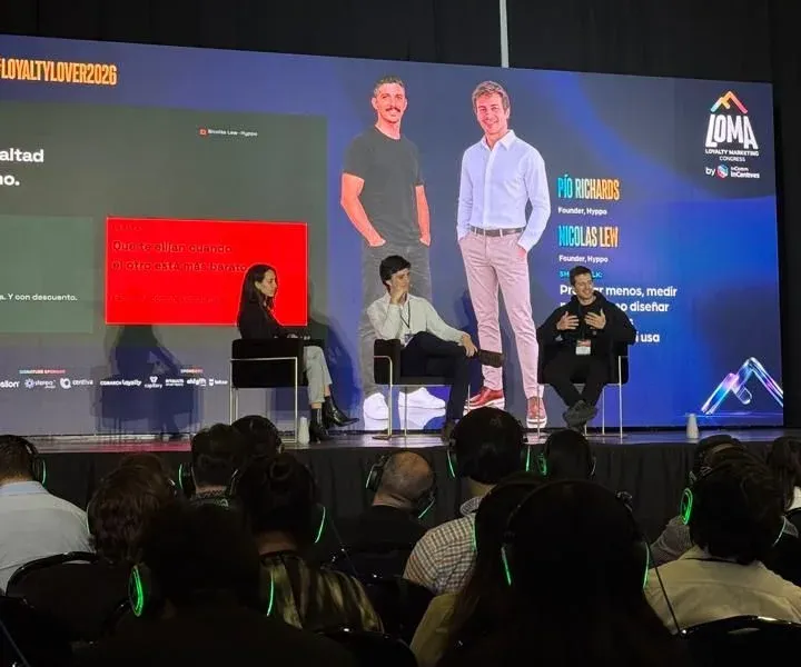 De izquierda a derecha, Talji Aziz de Customer.io, Pio Richards y Nicolás Lew de Hyppo en el escenario de LOMA 2026, con la lámina de retención y lealtad en pantalla